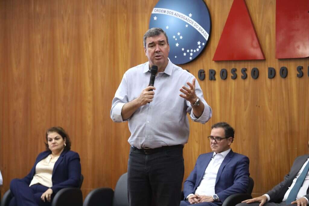 Governador Eduardo Riedel veste camisa cinza e calça jeans preta.