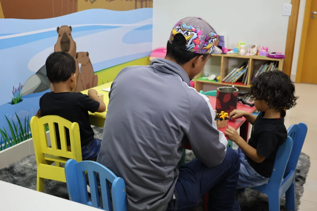 Crianças brincam com o pai em um espaço alegre e colorido.