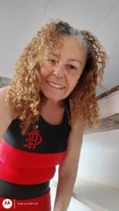 Beneficiária Quitéria Bernado da Silva usando uma camiseta regata do Flamengo.